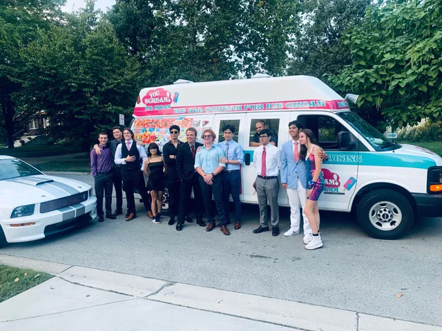 A group of guests in formal dress posing in front of the ice cream truck at an evening event