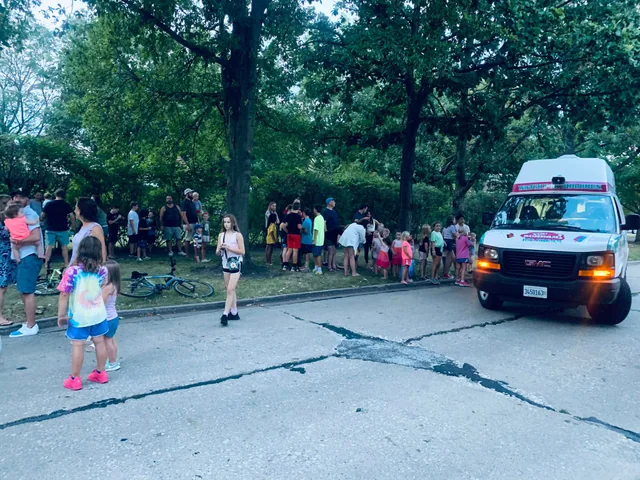 A long line of schoolchildren waiting at the ice cream truck on a neighbourhood street